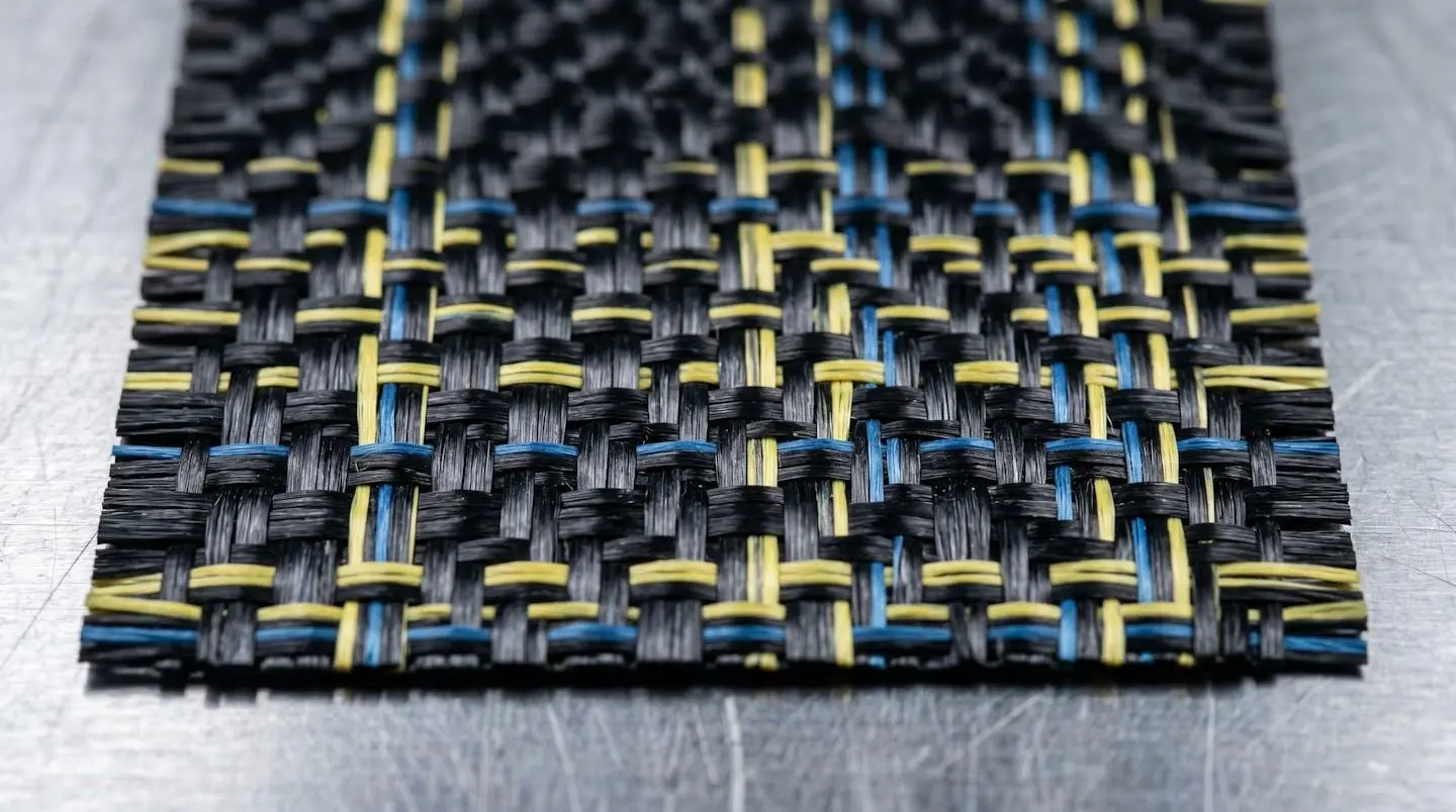 Tissu composite carbone-aramide haute résistance avec structure fibreuse entrecroisée visible en gros plan, utilisé pour applications aéronautiques et industrielles